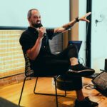 A speaker dynamically engaging the audience during an indoor event, emphasizing interaction and discussion.