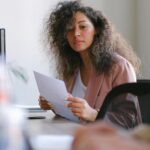 Confident businesswoman reviewing documents in modern office setting, focused and professional.